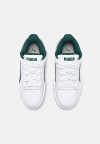 Baskets de sport blanches avec une finition texturée, ornées d'accents et de lacets verts, et de rayures noires sur les côtés. Logo imprimé sur la languette.