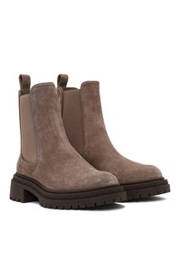 Bottines Chelsea en suède marron avec un panneau central lisse, des inserts élastiques sur les côtés, des languettes de tirage et une épaisse semelle en caoutchouc crantée.