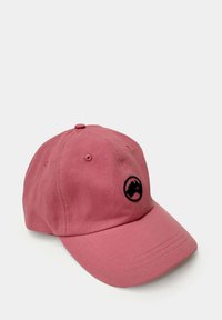 Gorra de béisbol de algodón rosa con visera curva, logotipo circular negro con la silueta de una montaña y ojales cosidos para ventilación.
