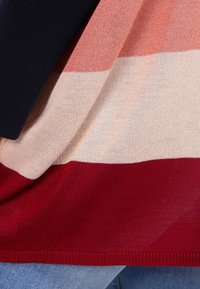 Sweter dziany z poziomymi paskami w kolorach granatowym, różanym, kremowym i bordowym. Miękka faktura z prążkowanym obszyciem i luźnym krojem.