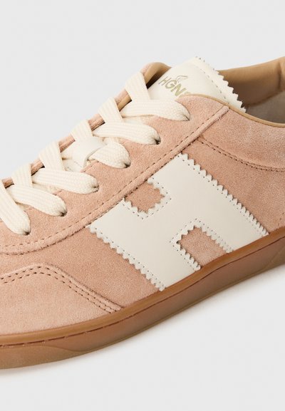 Tan suede kengät, joissa on kerma-accentit, aaltonainen muotoilu, teksturoitu pinta ja pyöreät nauhat. Kauttaaltaa kumipohja tarjoaa pitoa.