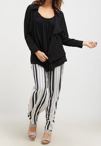 Black lightweight cardigan over a black gathered tank top; paired with white and black striped wide-leg pants. Gray open-toe heels.