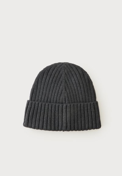 Bonnet tricoté gris foncé avec motif côtelé vertical et revers plié sur un fond clair uni.