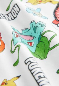 Tkanina w motywy Pokemon, przedstawiająca różnorodne kolorowe postacie, głównie zielonego Bulbasaura, na białym tle z rysunkowymi wzorami.