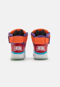 Baskets hautes avec un corps en cuir rouge, des accents orange et violet, un logo Ewing blanc à l'arrière, et une semelle bleu clair.