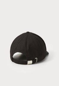 Black cap with a curved brim, cotton fabric, adjustable strap at the back, and a small metallic buckle. Two ventilation holes visible.