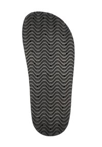 Semelle de chaussure en caoutchouc noir avec un motif ondulé et de petits trous de drainage, offrant texture et adhérence pour une meilleure traction et durabilité.