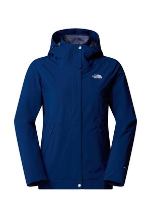 Chaqueta impermeable azul con capucha, bolsillos con cremallera y un pequeño logo en el lado izquierdo. Textura suave y diseño ajustado.