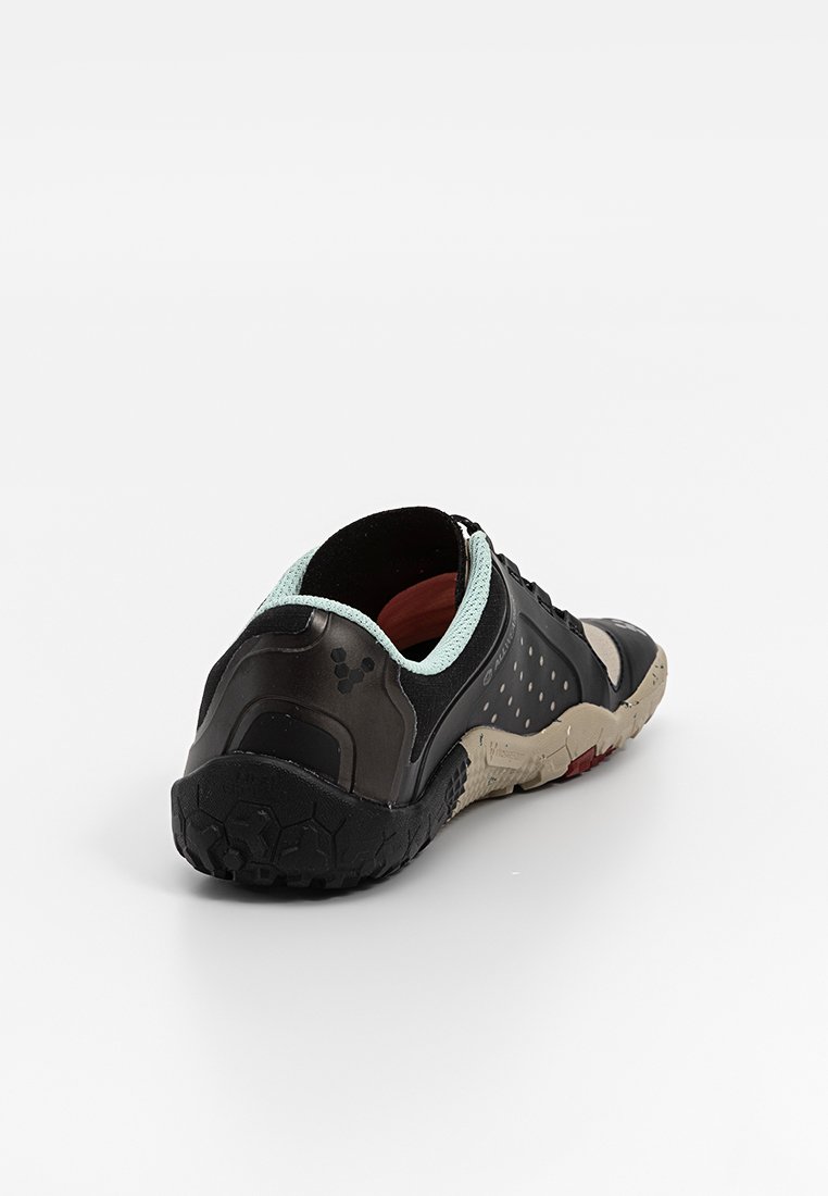 Zapatilla deportiva negra con una superficie texturizada, acentos en azul claro y una suela resistente. La parte trasera presenta un talón redondeado y agujeros de ventilación.