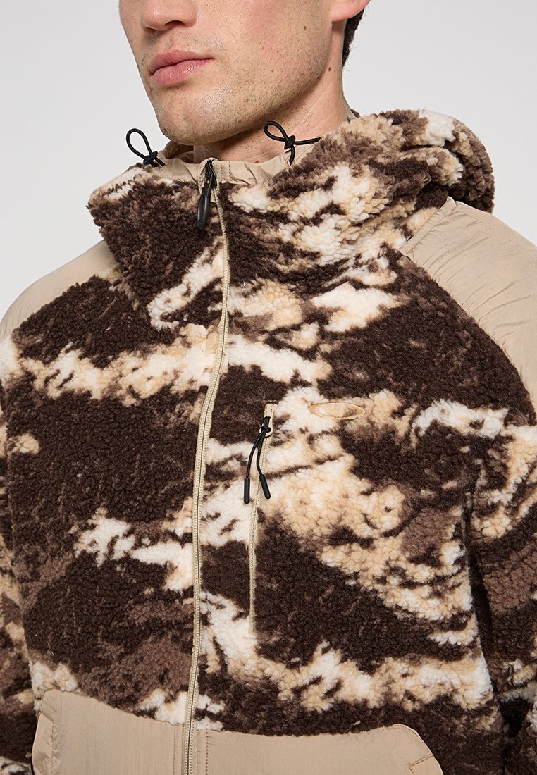 Veste en polaire marron et beige avec un motif texturé semblable à des nuages. Elle possède une capuche, une fermeture éclair à l'avant et des cordons réglables au niveau du cou.