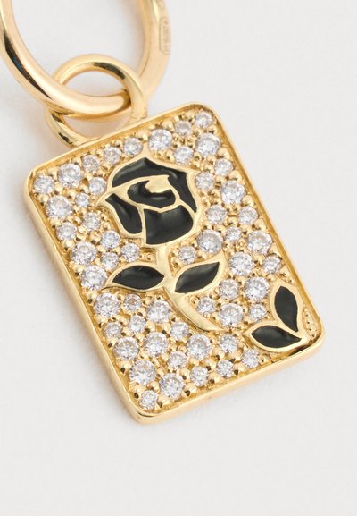 Rechteckiger goldener Anhänger mit schwarzem Emaille-Rose und Blättern, umgeben von klaren, funkelnden Kristallen, befestigt an einem goldenen Ring.