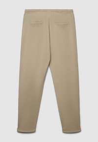Beige Jogginghosen mit elastischem Bund, zulaufenden Beinen und zwei Gesäßtaschen. Hergestellt aus weichem, glattem Stoff mit dezenter Textur.