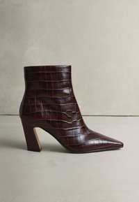 Brauner Leder-Stiefelette mit spitzer Zehenpartie und strukturiertem Krokodilmuster. Verfügt über einen Blockabsatz und eine glatte Oberfläche.