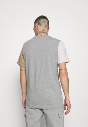 Grijs T-shirt met een ronde hals, met drie mouwen in blokkleuren: beige, grijs en lichtgrijs. Gemaakt van zacht katoenmixmateriaal.