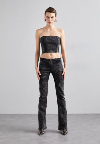 Black denim two-piece outfit featuring a strapless cropped top and flared pants, with subtle texture and zippers at the front.