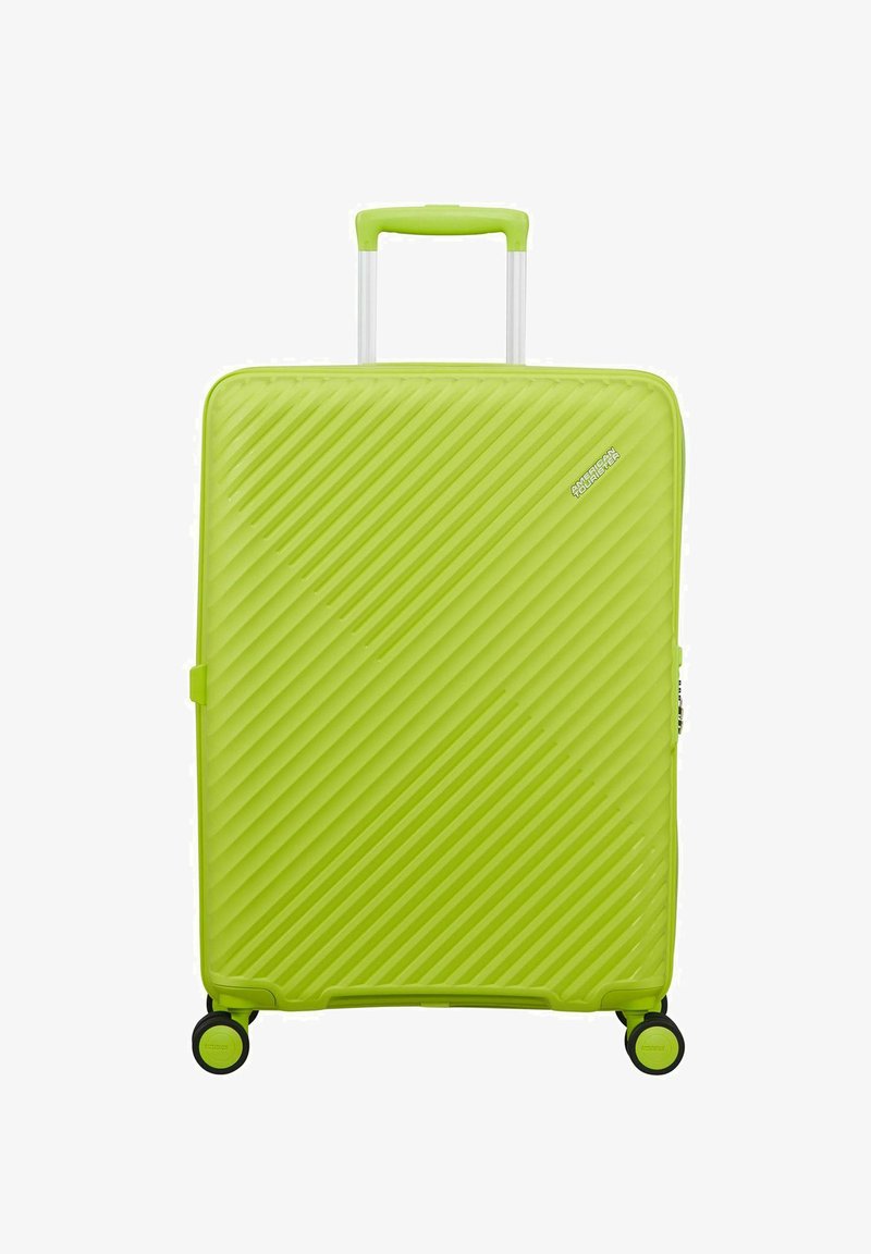 Valise rigide vert vif avec des rainures diagonales, quatre roues pivotantes noires et vertes, et une poignée rétractable.