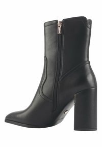 Black leather ankle boot with a pointed toe, side zipper, and a chunky high heel. Features a smooth texture and subtle stitching detail.