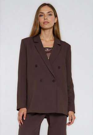 Brązowa dwurzędowa marynarka z klapowanym kołnierzem, gładką teksturą i dwoma przednimi guzikami, zestawiona z siateczkowym topem w dopasowanym odcieniu.