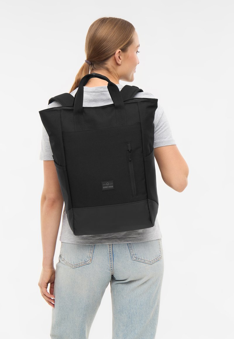 Fekete hátizsák strukturált dizájnnal, szövet anyagból, elülső cipzáras zsebbel és rövid fogantyúval, elülső logóval ellátott folttal.