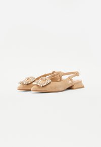 Chaussures à talon carré bas en suède beige avec un unbridage, ornées d'un embellissement décoratif en strass à l'avant.