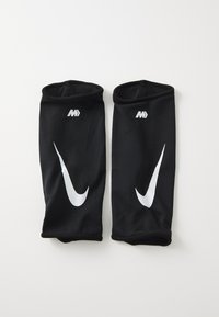 Sorte sportsarmærker lavet af mesh-stof. Har fremtrædende hvide Nike swoosh-logoer og elastiske åbninger øverst og nederst.