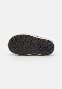 Suela de goma negra con un patrón en zigzag, detalle de borde blanco y acentos sutiles texturizados. Presenta marcas de la marca cerca del talón.