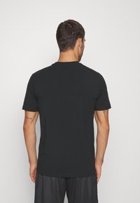 Czarny t-shirt z krótkim rękawem i okrągłym dekoltem, wykonany z gładkiej bawełnianej tkaniny, o klasycznym kroju, bez widocznych wzorów czy logo.