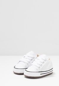 Vita canvas-sneakers med snörning, svarta detaljer, gummisula och texturerad design, lämpliga för vardagsbruk.