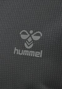 Sort sportsstof med en struktureret mønster og lyse turkise accenter. Et gråt "hummel" logo er tydeligt vist.