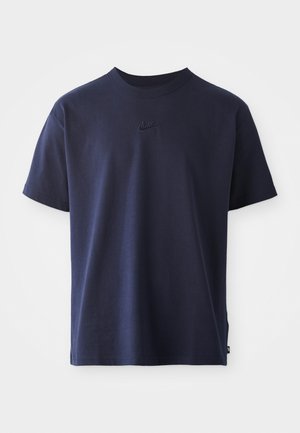 Granatowa bawełniana koszulka z okrągłym dekoltem, krótkimi rękawami i haftowanym logo na piersi. Gładka faktura, luźny krój.