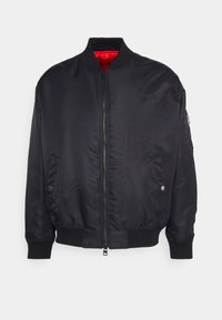 Giubbotto bomber nero con zip frontale, polsini e orlo a costine; presenta una fodera interna rossa e tasche laterali per riporre oggetti.