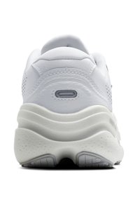 Balti sneakers ar teksturētu ādas augšdaļu, mīkstu polsterētu apkakli un masīvu baltu vidējo daļu ar viļņainu dizainu un smalkiem akcentiem.