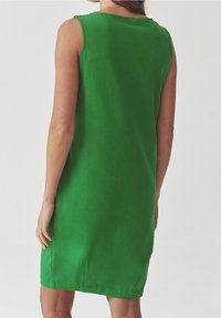 Green sleeveless dress in a smooth fabric with a simple design, featuring a round neckline and subtle side slits at the hem.