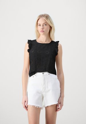Zwart mouwloos topje met bloemen uitsnijdingen, gerimpelde schouderaccenten, gecombineerd met witte rafelige denim shorts.