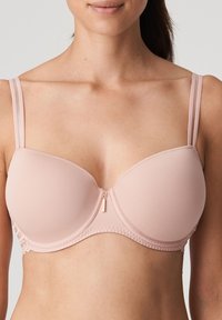 Light pink wireless bra with molded cups, adjustable straps, and lace trim along the band. Features a front clasp for closure.