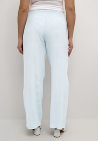 Pantalons larges à rayures bleu clair avec une taille élastique et une texture douce, présentant une coupe décontractée et un bas légèrement évasé.