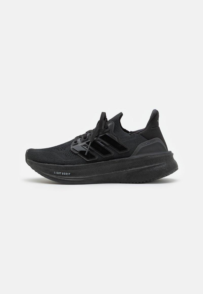Baskets de sport noires avec une tige en tricot respirant, un design texturé, les trois bandes emblématiques et une semelle épaisse et rembourrée portant l'étiquette "LIGHT BOOST".