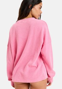 Rosa oversized hettegenser med teksturert stoff og dropped shoulders, med lange armer og rund hals.
