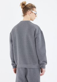 Grauer Sweatshirt aus weichem Material. Mit lockerer Passform, gerippten Bündchen und Saum. Glatte Textur und einfaches Design, keine sichtbaren Logos.
