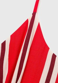 Tissu rayé rouge et crème avec des lignes verticales ; texture douce ; bretelles réglables ; présente un large décolleté.