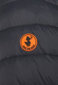 Zwart gevoerd stof met een oranje ronde patch waarop een cartoon-eend en de tekst "RED DE EEND" staat, op een jack.
