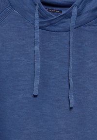 Modrá mikina s kapucí vyrobená z měkké, texturované tkaniny, s širokou kapucí, šňůrkami a jemnými žebrovanými akcenty na límci a ramenou.