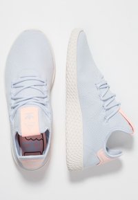 Ljusblå mesh-sneakers med en texturerad ovansida, vit gummisula och mjuka rosa accentfärger på hälen och tungan.