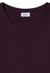 Fioletowa bawełniana koszulka z krótkim rękawem, okrągłym dekoltem i metką z napisem "CECIL". Gładka faktura, brak widocznych wzorów lub elementów metalowych.