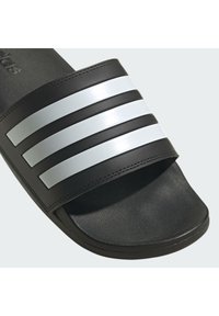 Black slide sandal featuring a textured strap with three glossy white stripes, flat sole, and durable material for comfort.