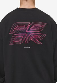 Schwarzer Sweatshirt mit einem großen, pinken und lila geometrischen Design auf dem Rücken, darunter befindet sich ein kleines weißes "PEPADOR"-Logo.