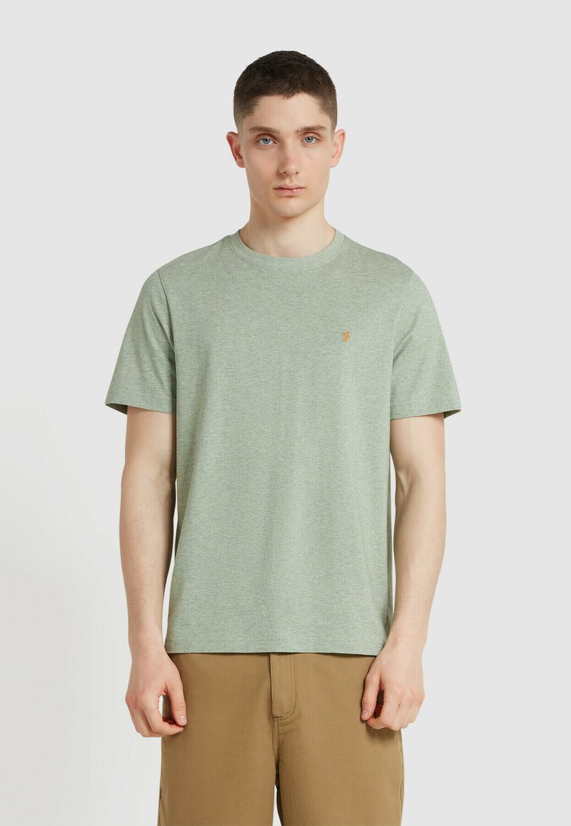 T-shirt di cotone verde chiaro con maniche corte, collo rotondo e un piccolo logo arancione sul petto. Design semplice e informale.