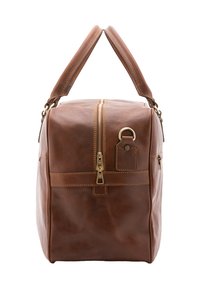 Sac de voyage en cuir marron avec deux poignées, fermeture éclair dorée sur le dessus et attache en D sur le côté, sur fond blanc.
