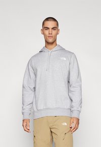 Sudadera gris con capucha ajustable y bolsillo delantero. Presenta un pequeño logotipo blanco en el pecho y puños y dobladillo acanalados.