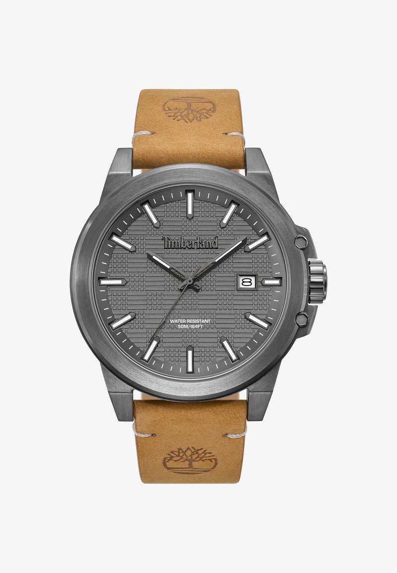 Reloj analógico gris con dial con patrón, marcadores de hora plateados y correa de cuero marrón con logotipo. Resistente al agua hasta 50 m.